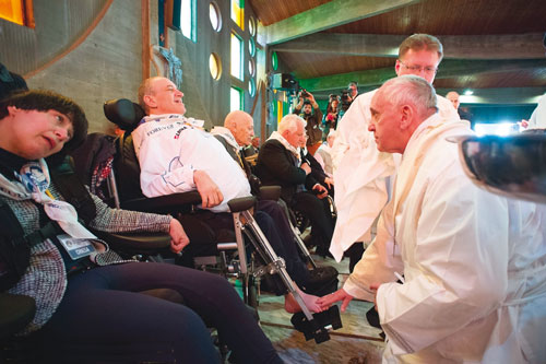 De paus wast en kust de voeten van arme gebrekkigen op Witte Donderdag.