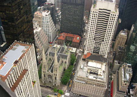 De Rooms-katholieke kathedraal van Sint-Patrick in New York wordt volledig overschaduwd door de wolkenkrabbers van het Amerikaans kapitalisme : een metafoor voor de geschiedenis van de Kerk in de VS.