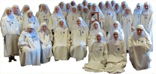 De communauteit van de Kleine Zusters van Maria Moeder van de Verlosser in hun traditionele kledij. Een van de religieuzen heeft het portret van de stichtster vast.